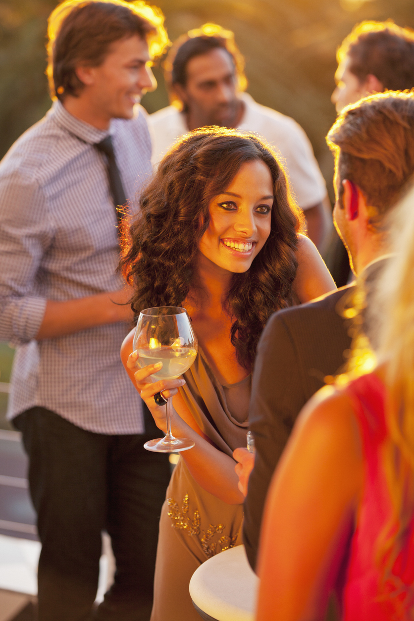 Smiling woman with wine glass talking to man on sunny balcony